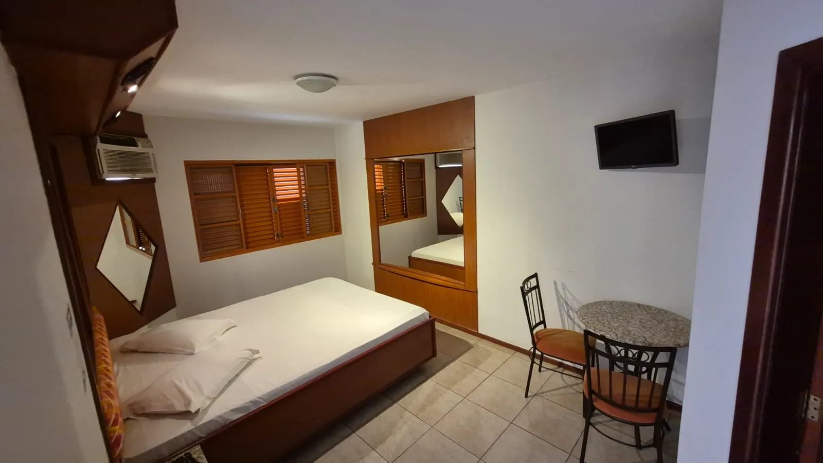 Suíte Standard do Motel Pousada Aquarius com cama de casal, ar condicionado e mesa para dois